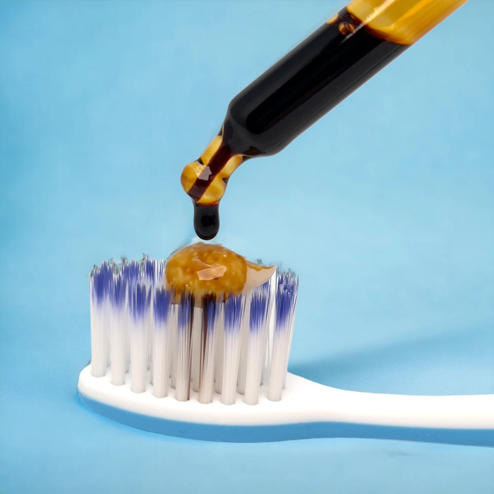 Das Bild zeigt eine Zahnbürste mit Zahnpasta, auf diese ein Tropfen Propolis getropft wird, damit es an den Zähnen angewandt werden kann