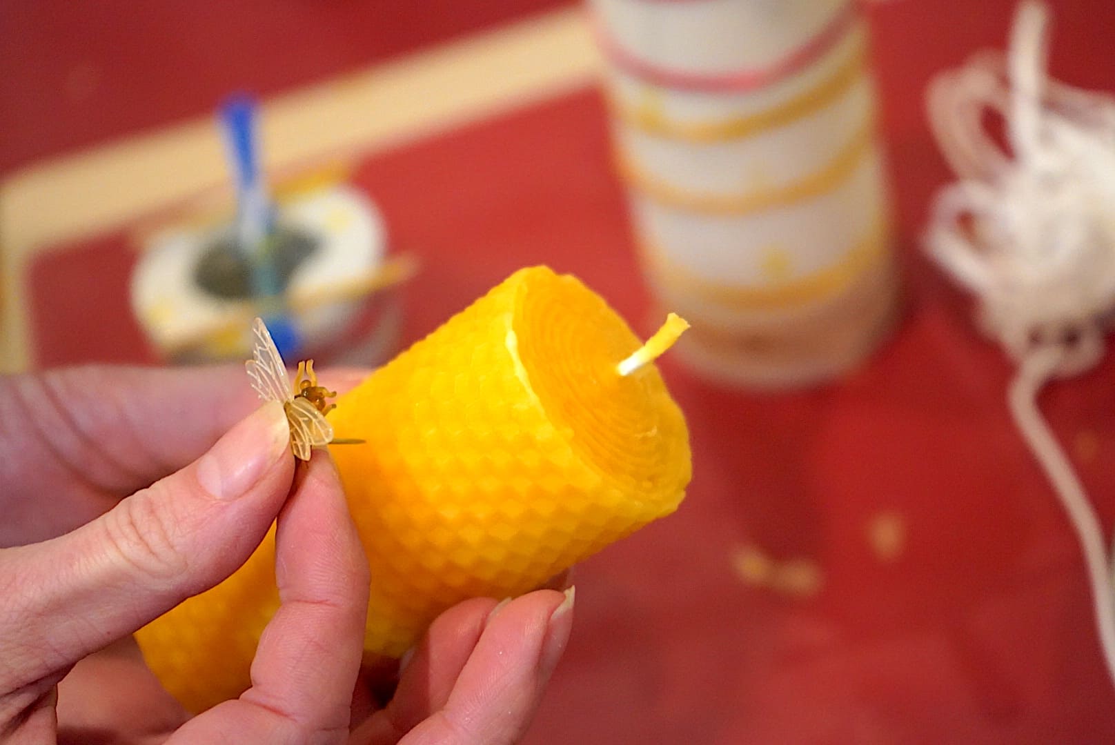 eine dekorative Biene wird in die handgemachte Bienenwachskerze gedrückt